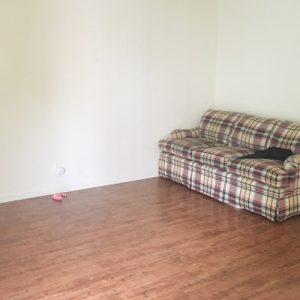 A single couch in Sarah's living room before the gathering.