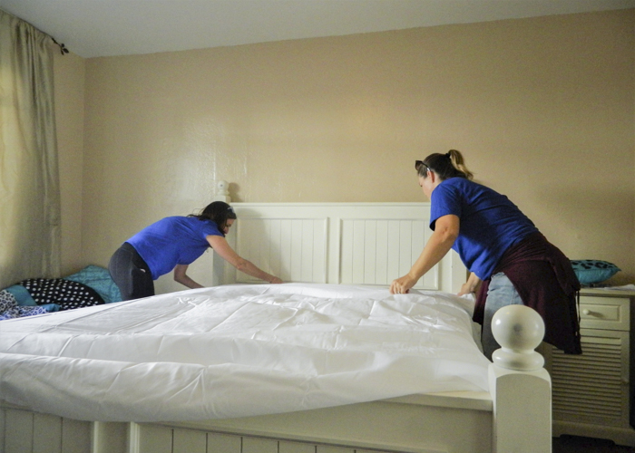 Two women setting up a bed