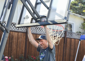 Man pushing basketball hoop upright.