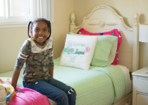 Young girl sitting on her new bed.