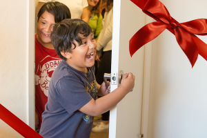 A smiling child bursts through the doorway into his new home