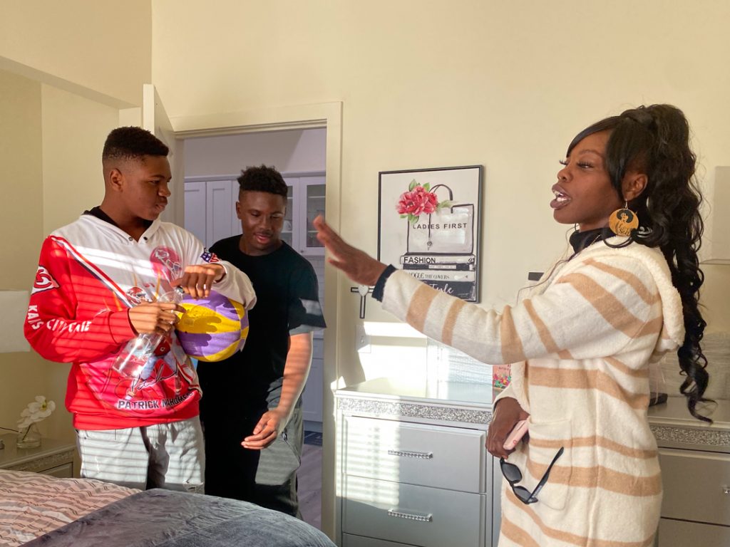 Melisha and her two sons reacting to Melisha's new bedroom. Melisha is showing her sons the new decorative bedding and decor.